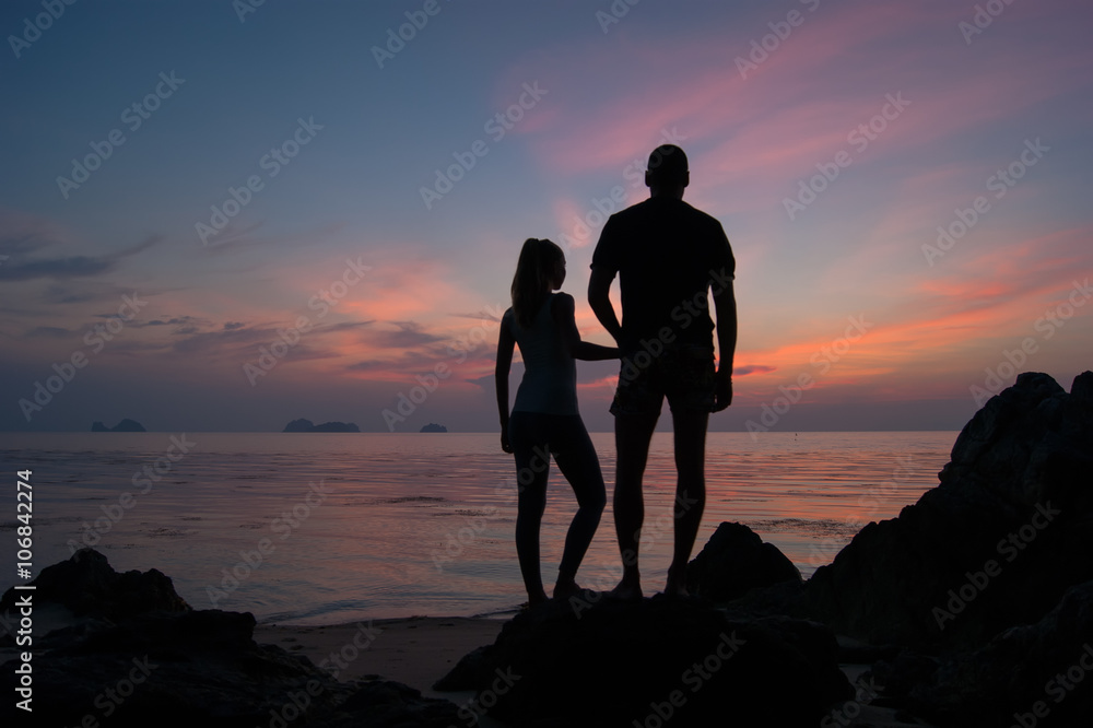 Young couple watch a decline, the Guy with the girl stand on the seashore and look in a distance,