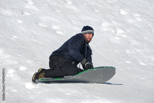 Man sledding down a snowhill photo