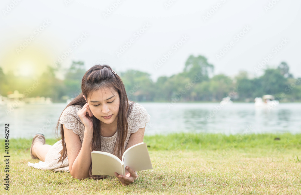 Woman lying on grass field for reading in the park