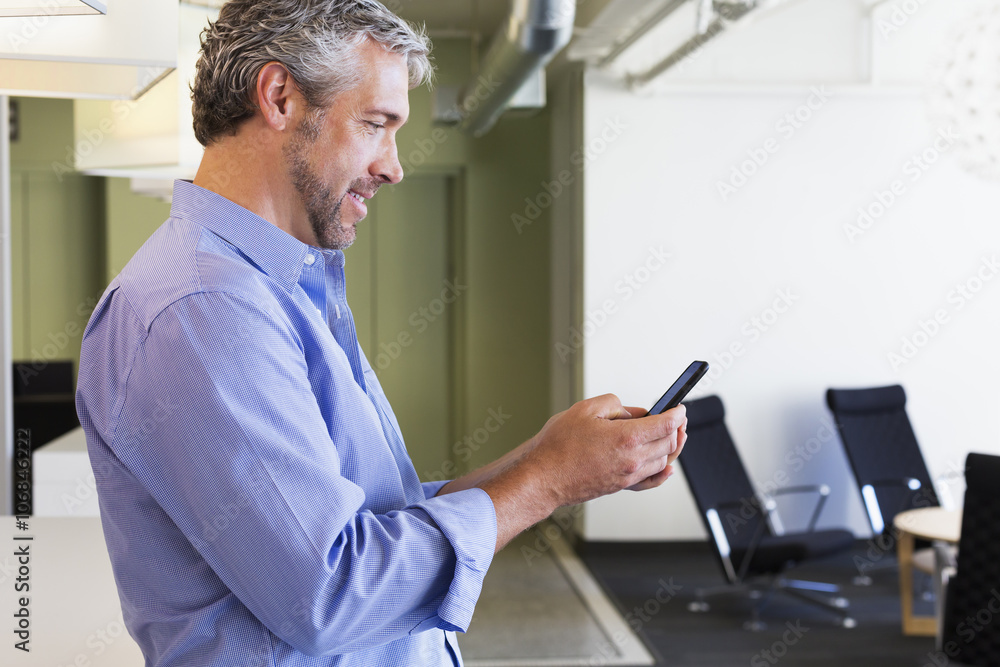Caucasian businessman using cell phone in office Caucasian businessman using cell phone in office