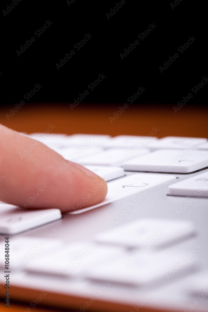 Finger pressing an enter button on alluminium keyboard with blac Finger pressing an enter button on alluminium keyboard with blac