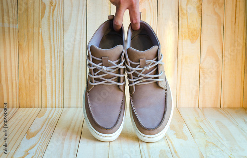 gray suede shoes holding by hand on wooden background