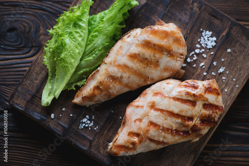 Top view of grilled chicken breasts and green salad, close-up