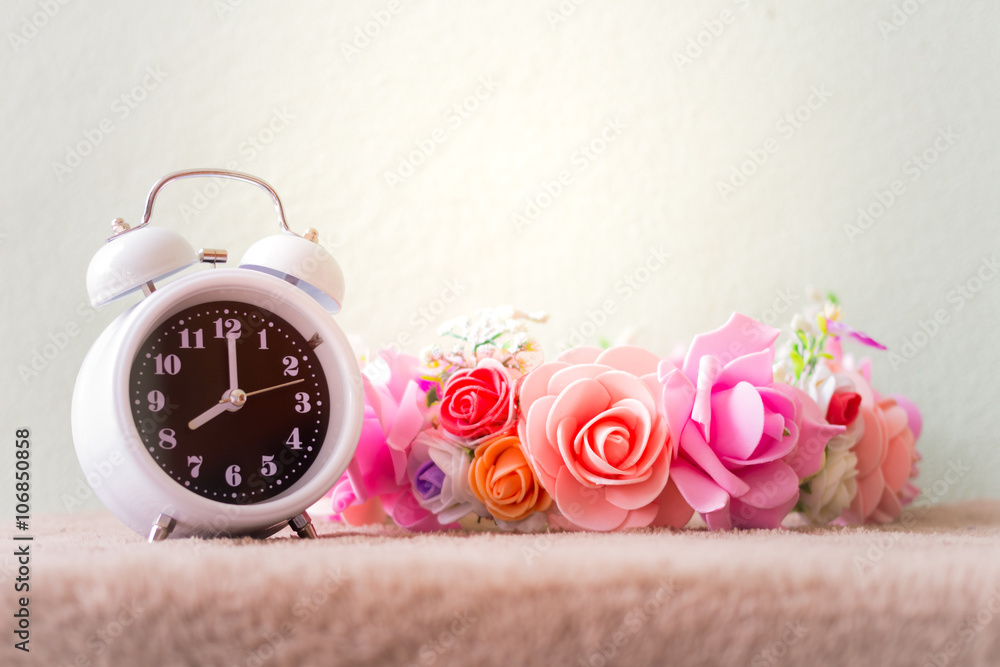 White clock with flowers on a table in muted vintage retro style White clock with flowers on a table in muted vintage retro style