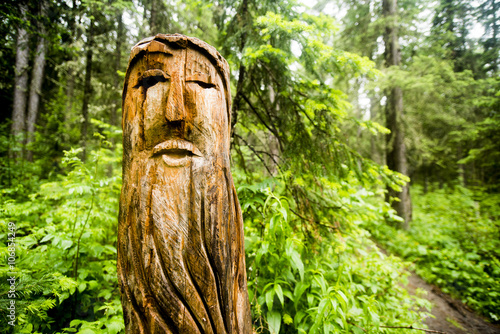 Close up of carved totem pole near forest path photo