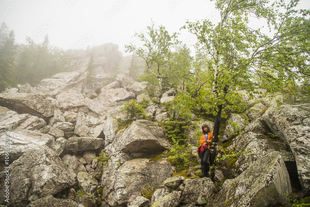 Caucasian hiker standing under tree on rocky hillside Caucasian hiker standing under tree on rocky hillside
