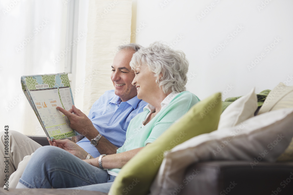 Older couple reading paperwork on sofa Older couple reading paperwork on sofa