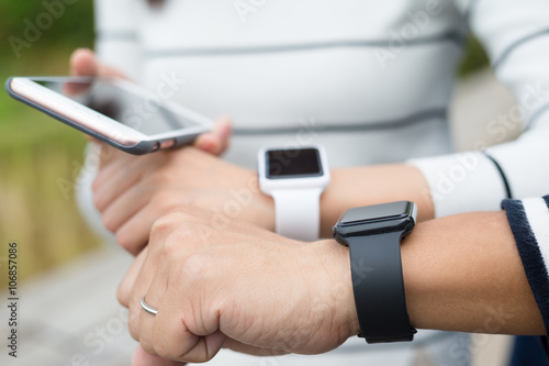 Two people using smartwatch together and connecting to cellphone