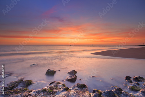 Beach with rocks at sunset in Zeeland, The Netherlands © sara_winter