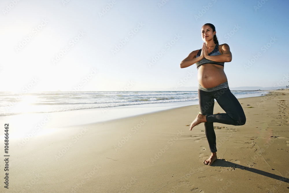 Pregnant Hispanic woman practicing yoga on beach Pregnant Hispanic woman practicing yoga on beach