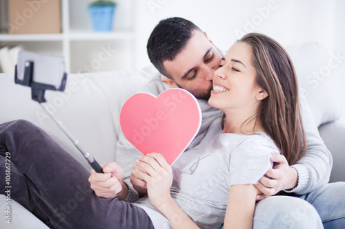 Valentines couple taking selfie and sharing cardboard heart and love,small depth of field