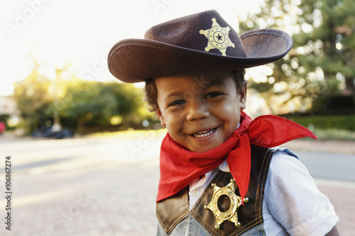 Mixed race boy in cowboy costume smiling outdoors photo