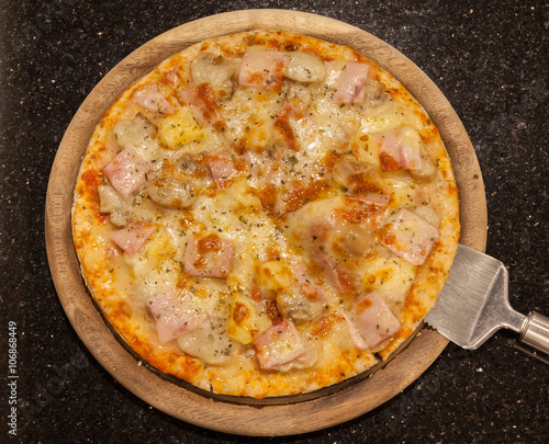 Sliced homemade ham and cheese pizza ready to served on wooden b