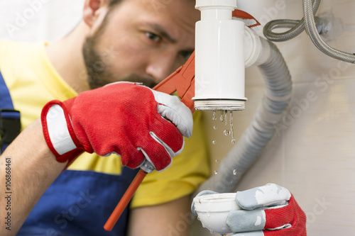 plumber fixing the sink siphon in a bathroom or kitchen photo