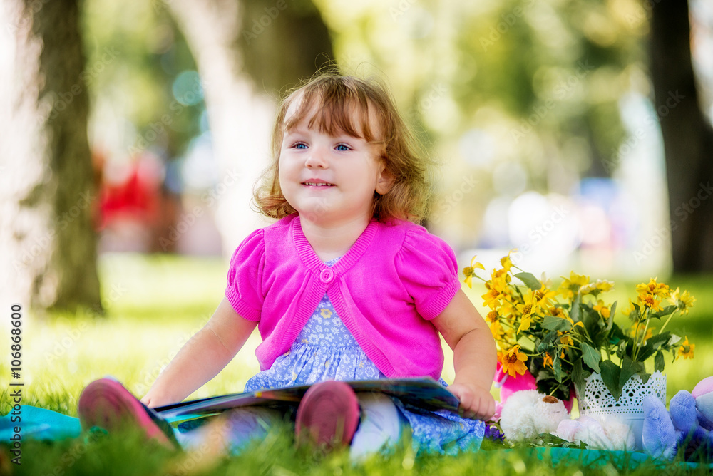 Little girl sitting in the park and reading a book Little girl sitting in the park and reading a book