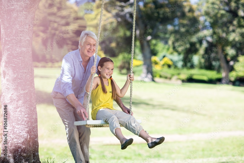 Grandfather pushing his granddaughter on swing