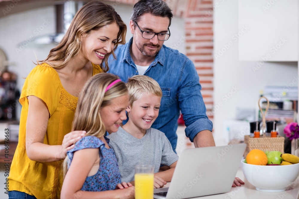 Parents and kids using laptop in kitchen Parents and kids using laptop in kitchen