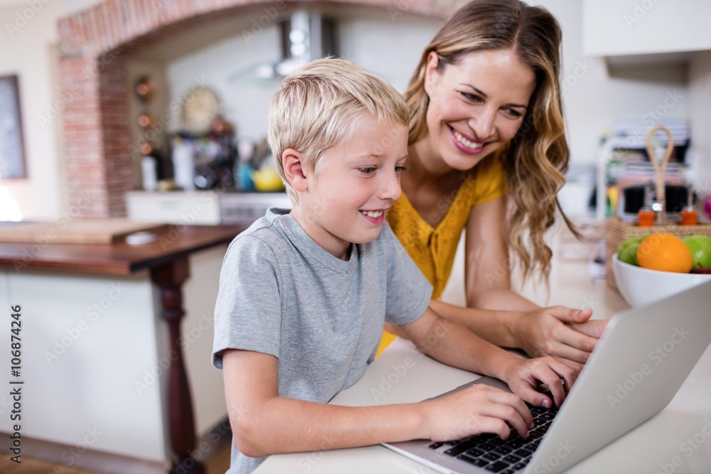 Mother and son using laptop in kitchen Mother and son using laptop in kitchen