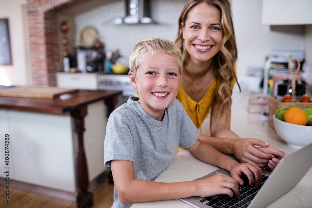 Portrait of mother and son using laptop in kitchen Portrait of mother and son using laptop in kitchen