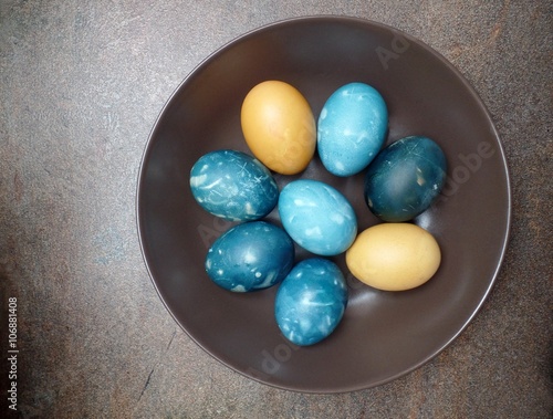 Blue and yellow easter eggs in brown plate