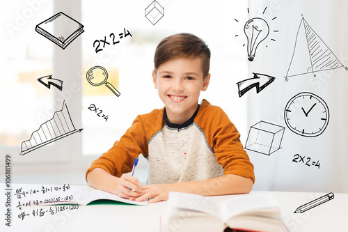 Fototapeta Naklejka Na Ścianę i Meble -  smiling student boy writing to notebook at home