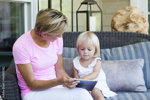 Caucasian mother and daughter using digital tablet on porch photo