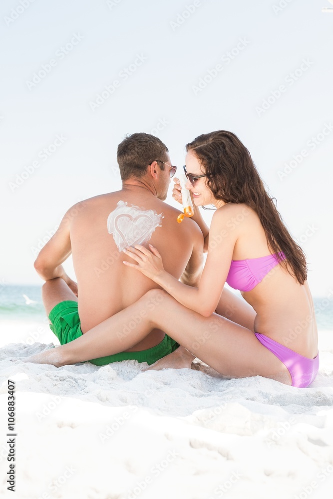 Girlfriend applying sun cream on boyfriend Girlfriend applying sun cream on boyfriend