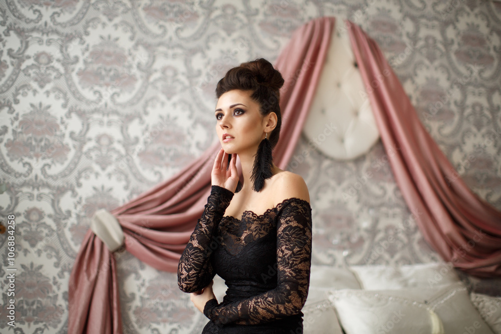 Fototapeta premium Beautiful model in black dress with evening makeup and hairdo posing