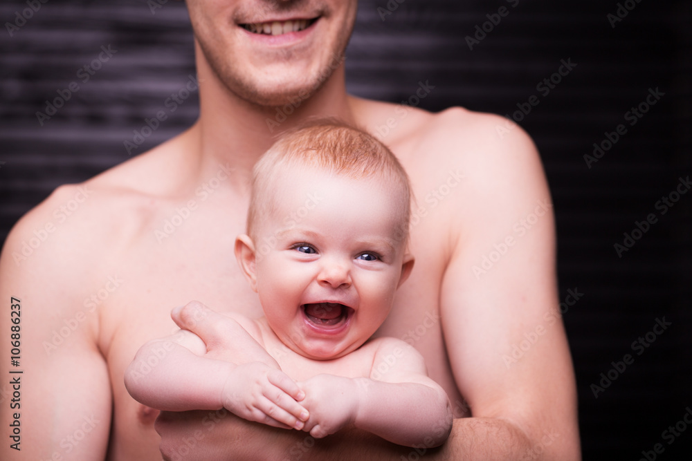 Young father is feeding his baby daughter.baby girl smiling at the hands of the father Young father is feeding his baby daughter.baby girl smiling at the hands of the father