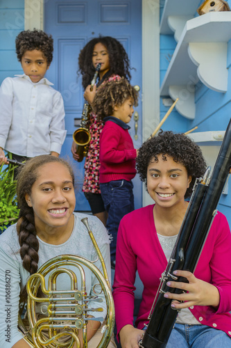 Pacific Islander family holding musical instruments on front stoop photo