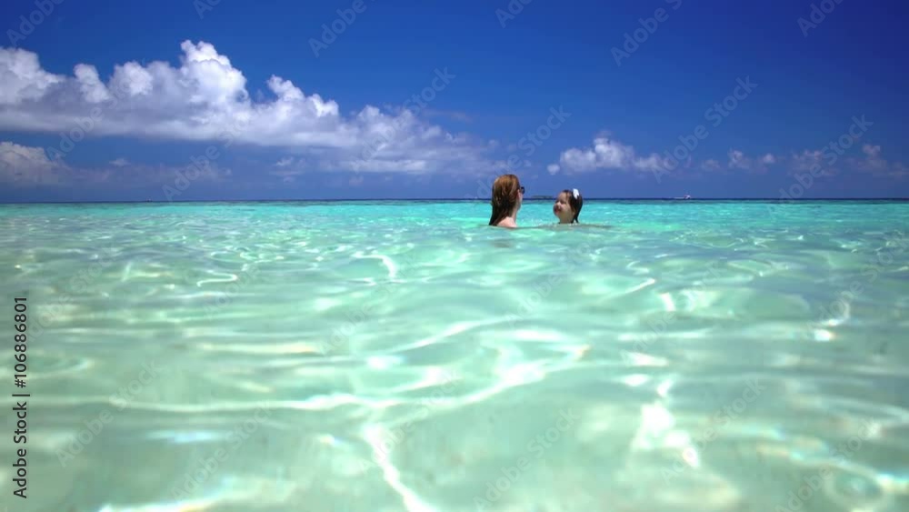 A young mother with her small daughter playing in the turquoise waves of the sea. A young mother with her small daughter playing in the turquoise waves of the sea.