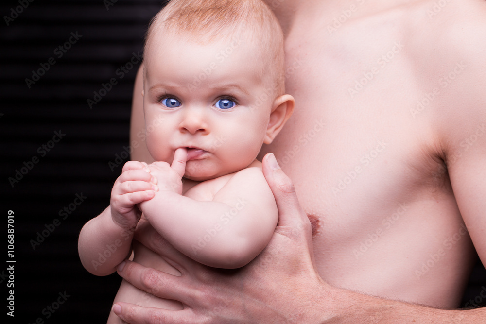 Young father is feeding his baby daughter.baby girl smiling at the hands of the father Young father is feeding his baby daughter.baby girl smiling at the hands of the father
