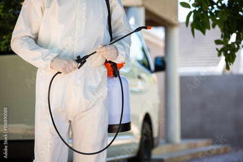 Mid section of pest control man standing next to a van photo