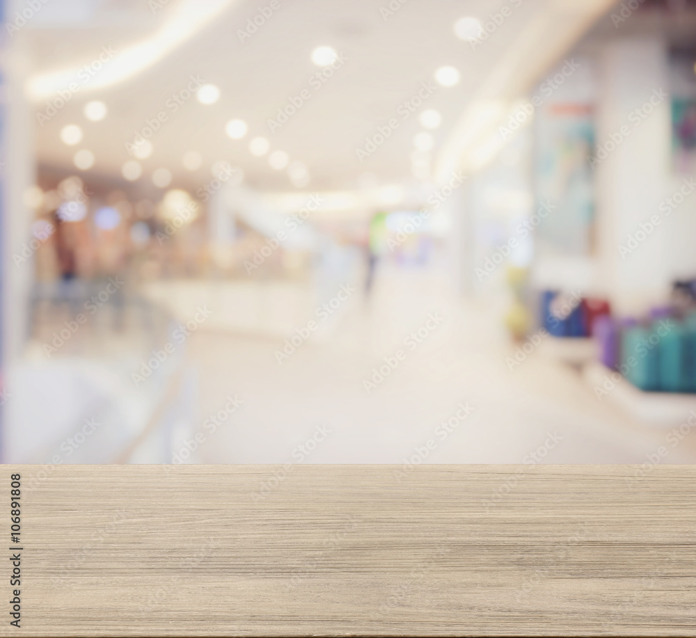 wooden table top with blur image of shopping mall interior with bokeh as background