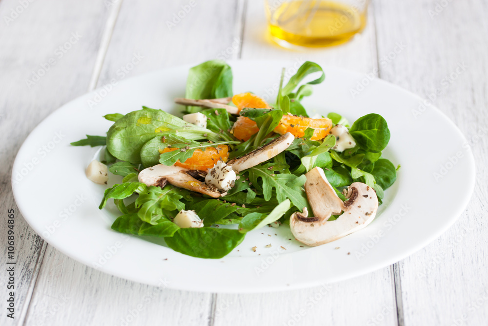 Sommer salad with rocket salad, mandarin, mushrooms and cheese gorgonzola in a white ceramic bowl , closeup.. Sommer salad with rocket salad, mandarin, mushrooms and cheese gorgonzola in a white ceramic bowl , closeup..
