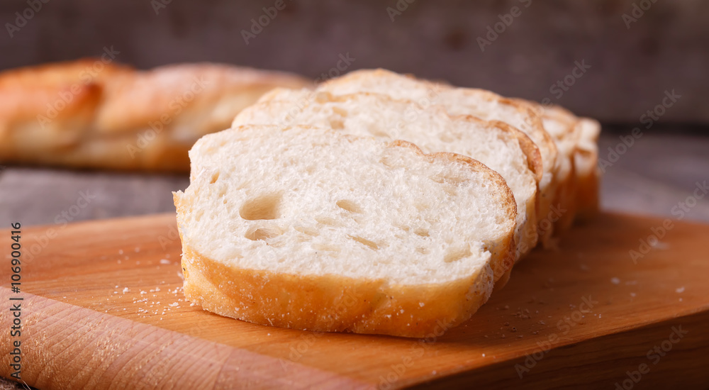 Freshly baked French baguette, sliced on a wooden board. In rustic style on sackcloth. Freshly baked French baguette, sliced on a wooden board. In rustic style on sackcloth.