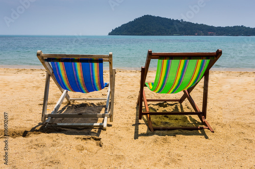 sun beach chairs on shore near sea.