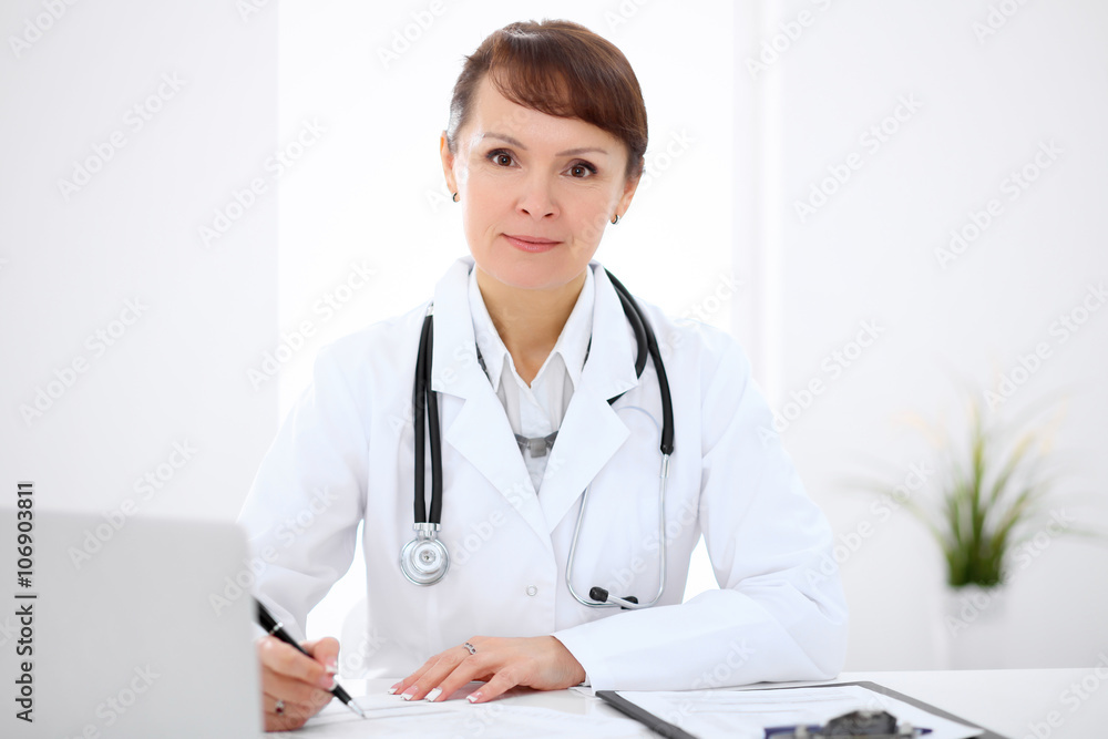Woman doctor filling up medical history at the desk Woman doctor filling up medical history at the desk