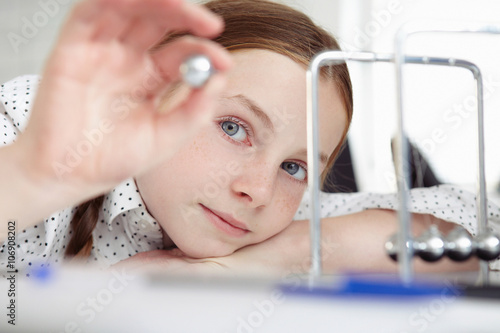 Girl playing with newton's cradle on desk photo