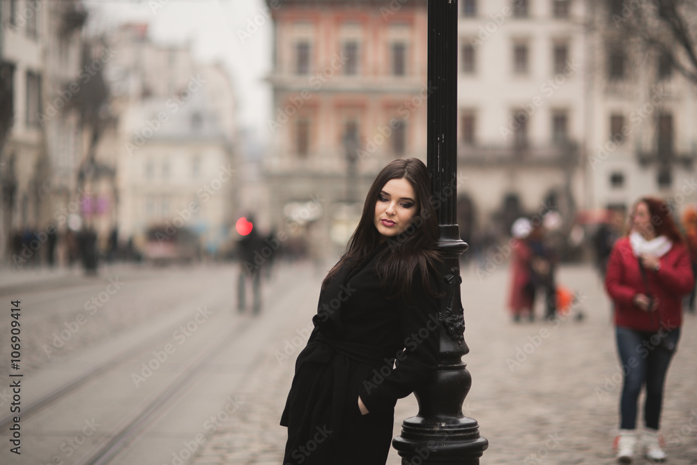 Fototapeta premium Beautiful brunette young woman posing on the street in old city