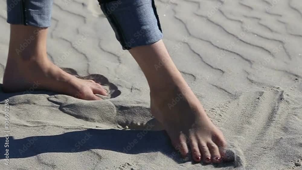 female feet digging into the warm sand of the sea beach