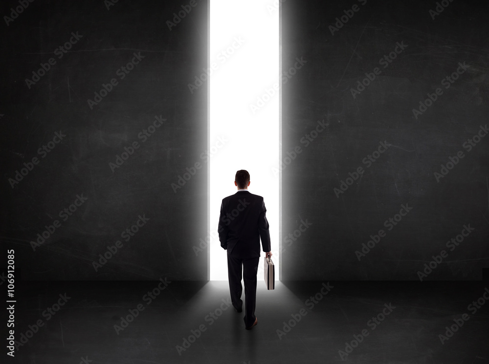 Business person looking at wall with light tunnel opening Business person looking at wall with light tunnel opening