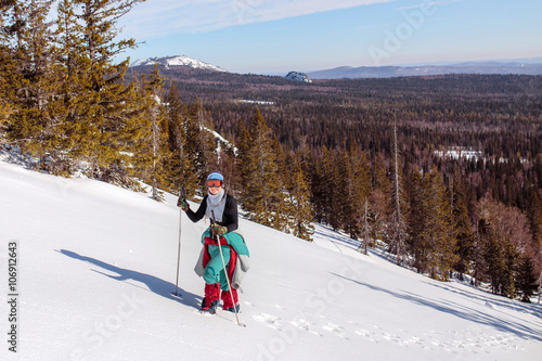 A female climber , dressed in red, climbs up a snowy slope of mo