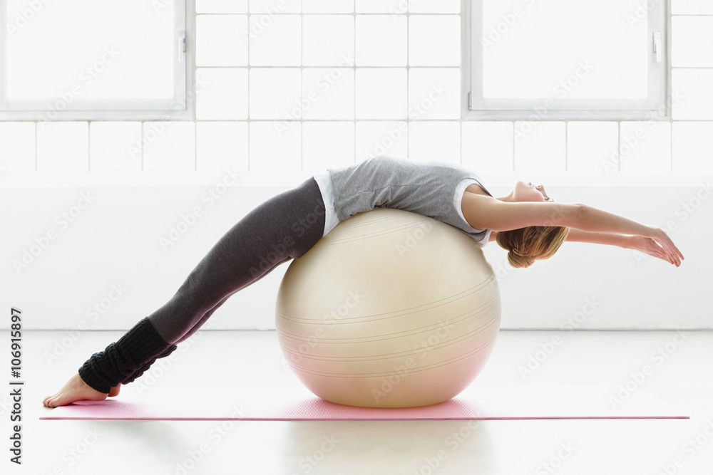 © Connect Images - Young woman stretching on exercise ball
