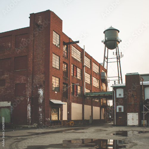 Factory with a water tower, brick building at sunset.