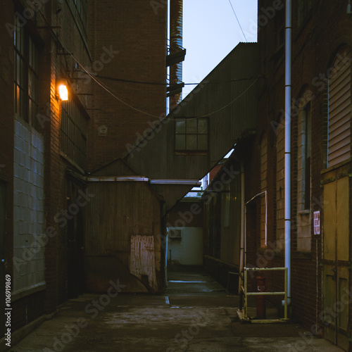 Looking down an old industrial alley during twilight, filtered image.