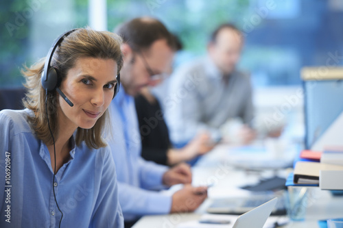 Woman wearing telephone headset in office