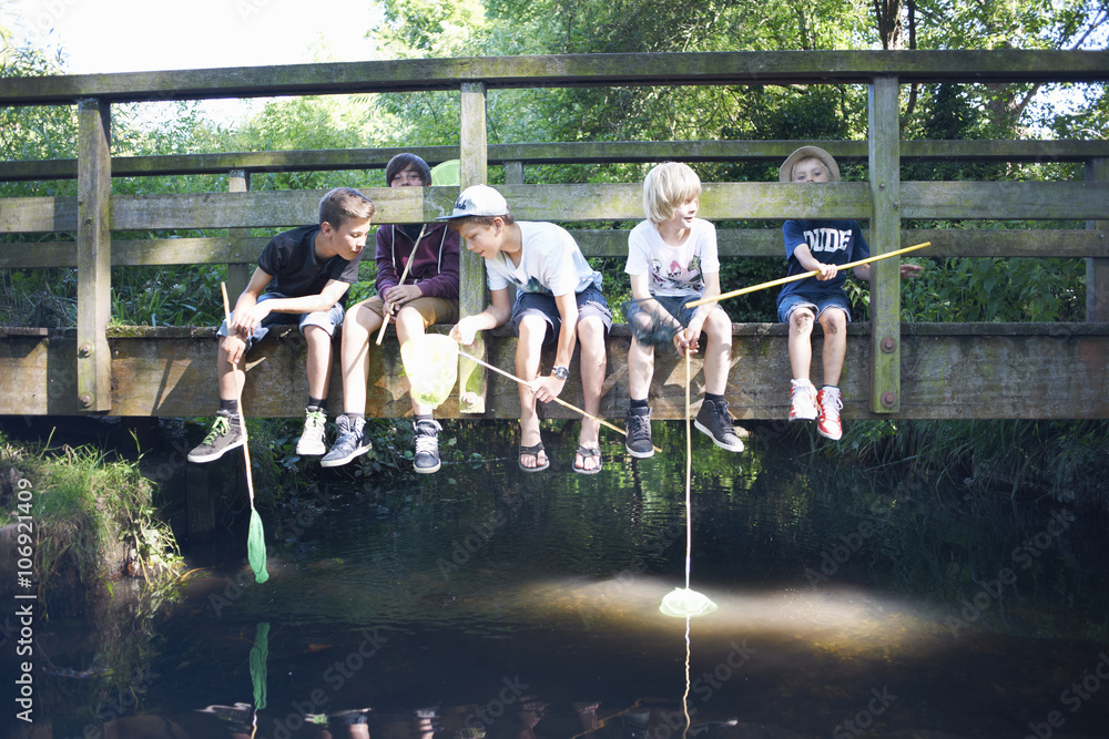 Boys sitting on bridge, fishing Boys sitting on bridge, fishing