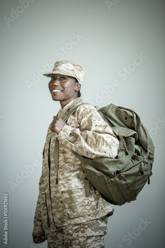 Side view studio portrait of confident female soldier with rucksack photo
