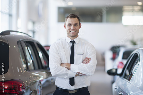 Portrait of smiling salesman in car dealership photo